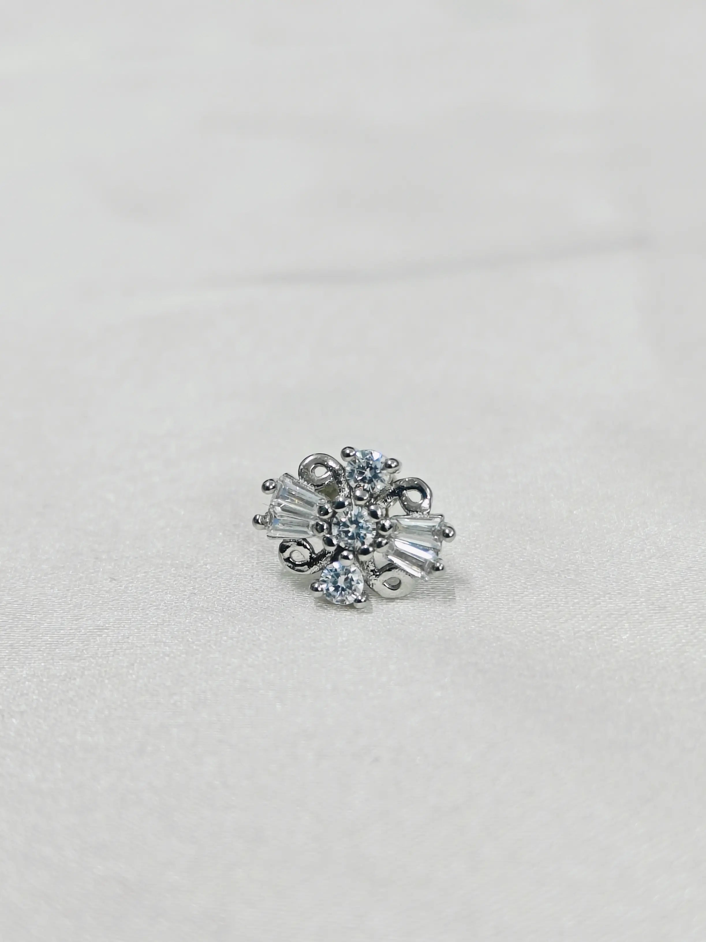 Silver earring with clear gemstones on a light gray background